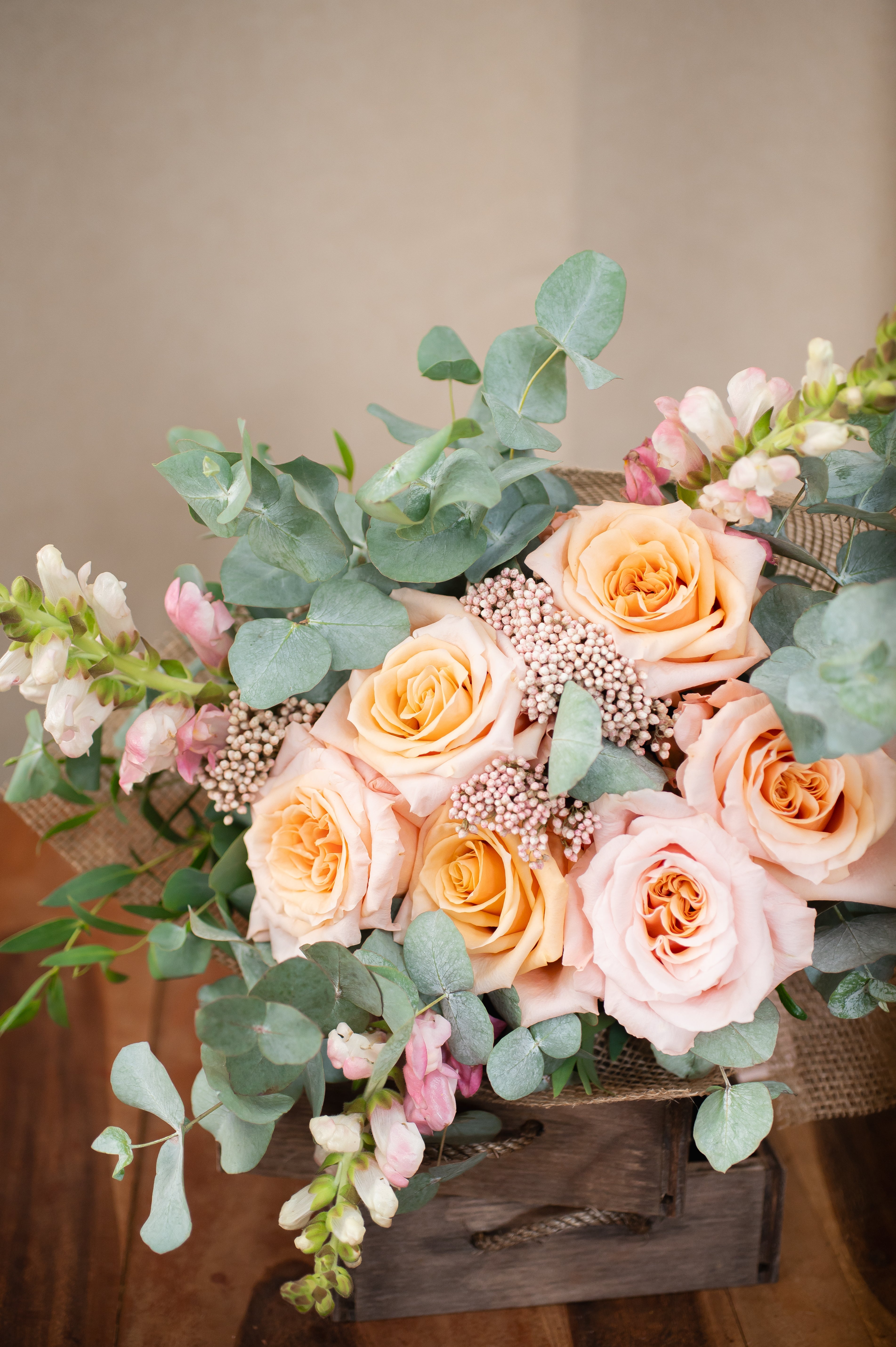 Elegant floral bouquet featuring peach and blush roses, eucalyptus, snapdragons, and delicate filler flowers. A perfect arrangement for weddings, gifts, or home decor.